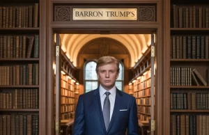 Barron Trump: The Personal Life and Emerging Publicity of the Youngest Son of Donald Trump The picture shows a young man wearing a sharp blue suit standing confidently in a fancy library hallway under the sign that says "Barron Trump s" with shelves of classic books around him.